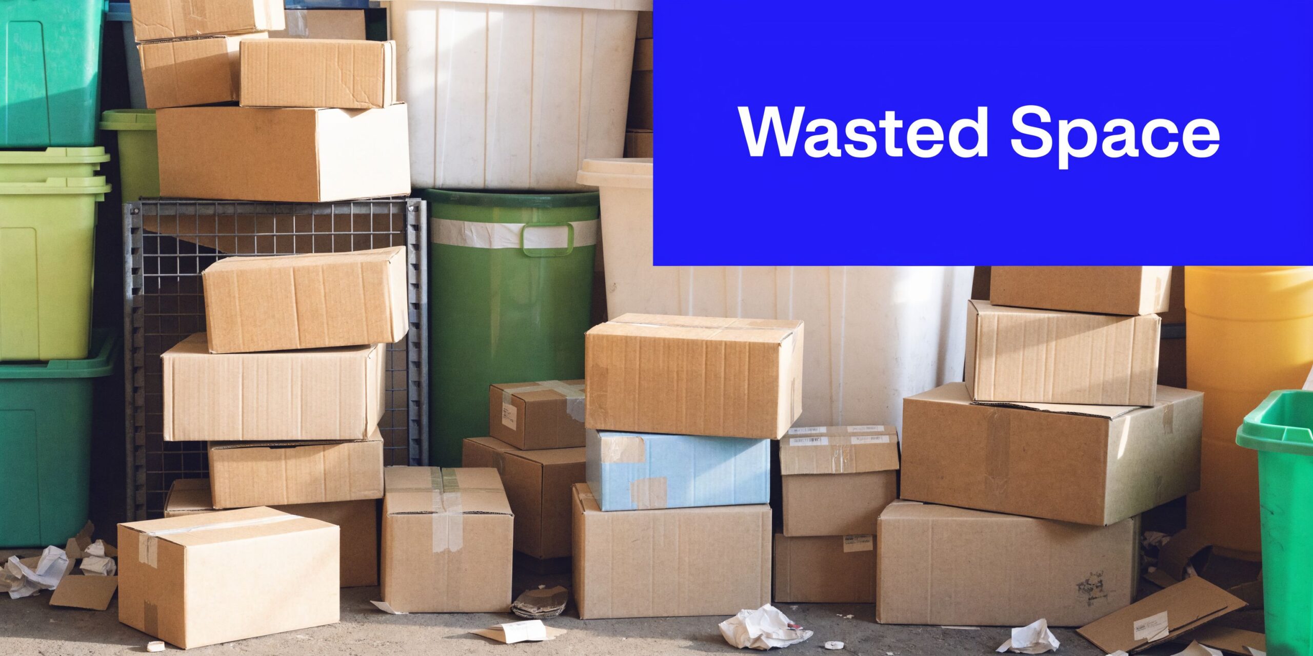 Stack of cardboard storage boxes and plastic bins piled in a cluttered warehouse space for organization.