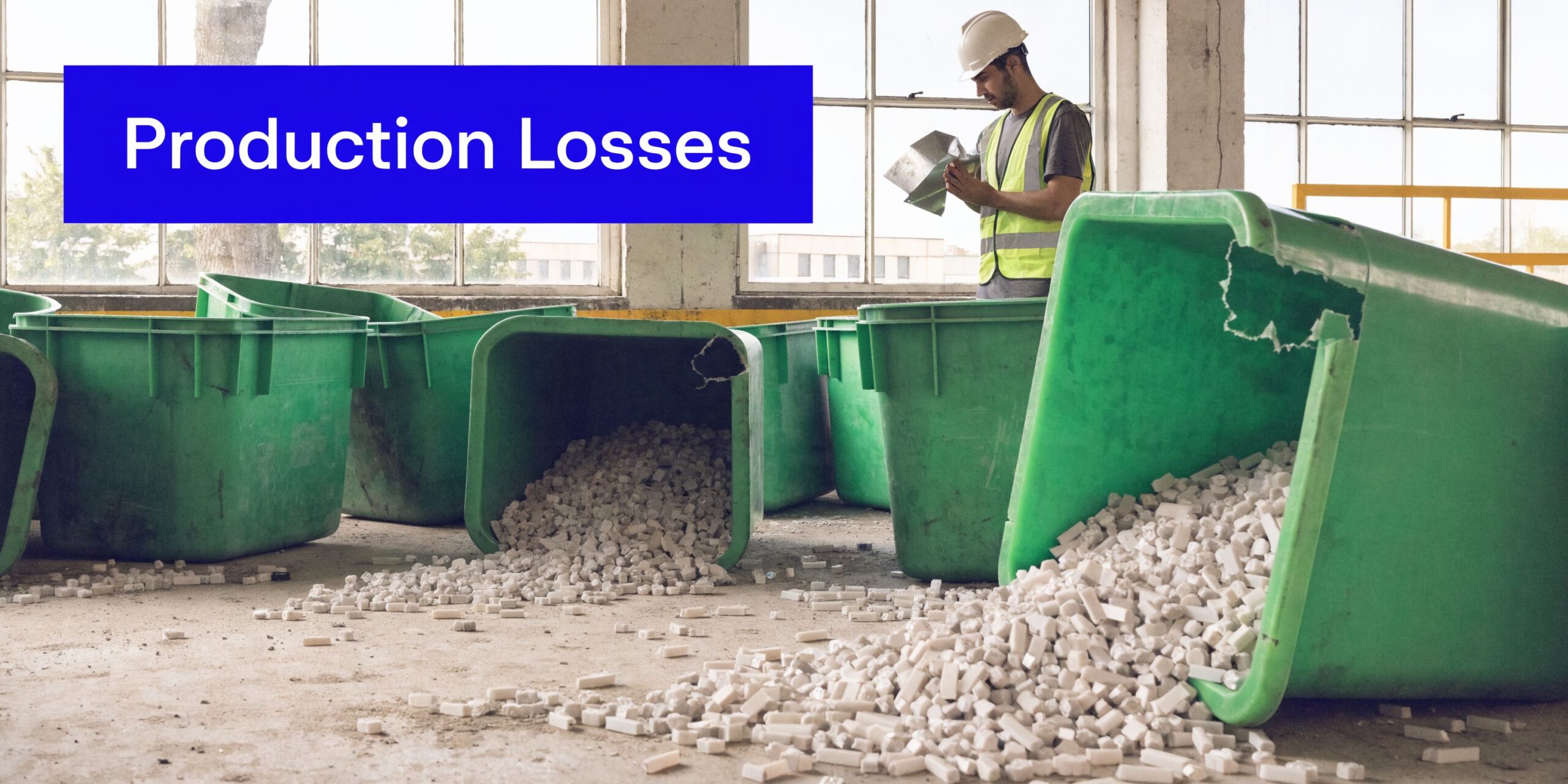 A factory worker inspects metal parts next to several large green bins filled with white plastic pieces.